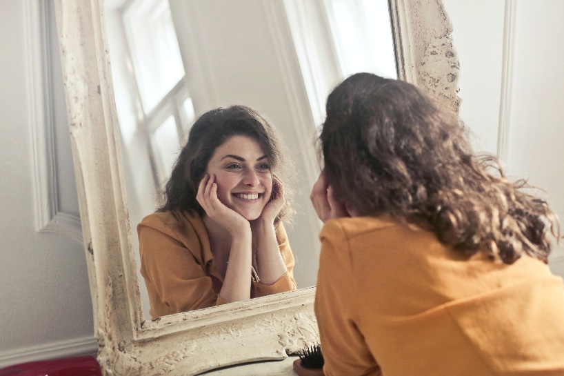 A women happily looking at herself in a mirror due to positive psychology