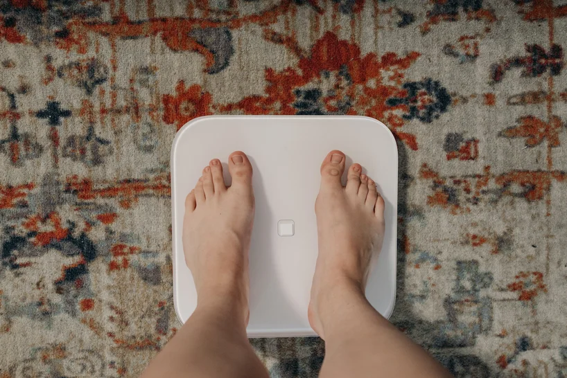 someone standing on a scale concerned about their weight due to an eating disorder (ed)