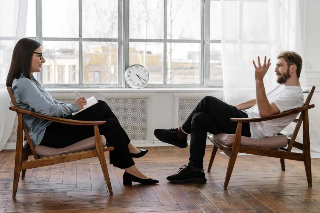 Two people sitting across from each other in a bright room